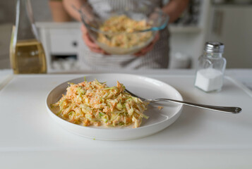 Fresh prepared coleslaw served by woman´s hands in the kitchen