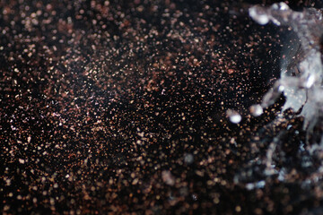 Macro shot of bronze and gold particles in water