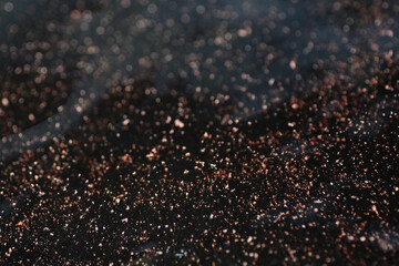 Macro shot of bronze and gold particles in water
