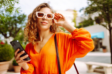 Young woman walking around the street use smartphone, communication with friends. Networks,...