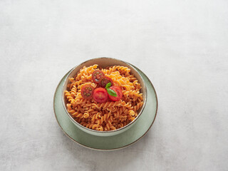 pasta spirals dish (fussili) of red lentils with colorful cherry tomatoes and fresh basil leaves
