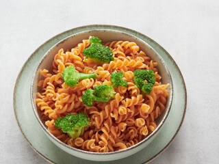 close-up of plate with red pasta spirals (fussili) and broccoli