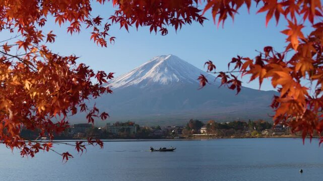 Mount Mt Fuji View through Red Maple Leaves in peak Autumn with Fisher's Boat on Lake Kawaguchiko