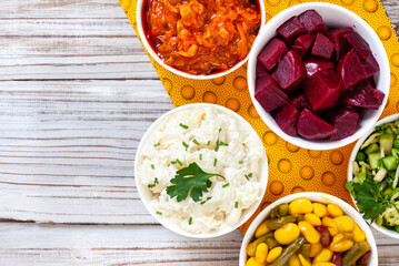 Traditional side dishes and salads for a perfect South African braai. Salads in bowls on Iconic South African printed fabric, Shwe Shwe. Rustic wooden surface with copy space