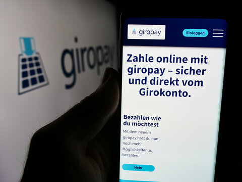 Stuttgart, Germany - 07-04-2024: Person holding cellphone with webpage of German payments company Giropay (Paydirekt GmbH) in front of logo. Focus on center of phone display.