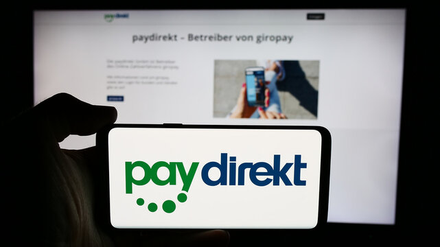 Stuttgart, Germany - 07-04-2024: Person holding cellphone with logo of German payment company Paydirekt GmbH (Giropay) in front of business webpage. Focus on phone display.