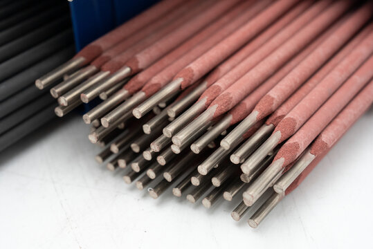Red welding rods and electrodes on a white background. Close-up of welding electrodes in industrial setting - Metal rods with protective coating. High-Quality electrodes for professional welding.