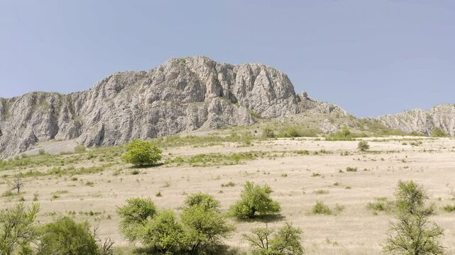 Slow, rising view of Piatra Secuiului, Romania, a barren, limestone mountain peak near villages of Rimetea and Coltesti