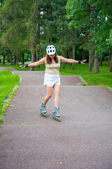 Roller skater woman in park rollerblading on inline skates. Outdoor activities. Summer roller...