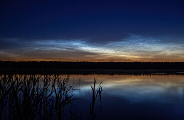 Lake at night, sky with stars, reflection in water, noctilucent clouds
