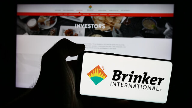 Stuttgart, Germany - 07-05-2024: Person holding smartphone with logo of US hospitality company Brinker International Inc. in front of website. Focus on phone display.