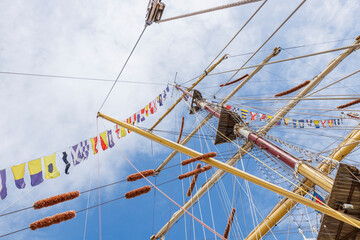 Sailing ship mast with flying nautical flags festival celebration decoration in a blue sunny sky...