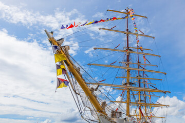 Sailing ship mast with flying nautical flags festival celebration decoration in a blue sunny sky...
