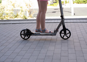 Fototapeta premium Teenage girl rides a scooter in a European yard