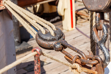 Sailing ship lines, pulleys and securing equipment tied down for the day. Deck and ropes, rigging on a wooden tall ship sail yacht. Close up view