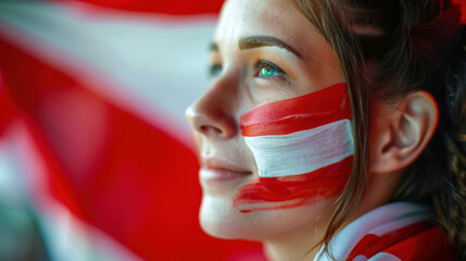 Close-up of a young woman with the Austrian flag painted on her cheek. A female cheerleader at a football match. The concept of patriotism and pride