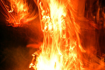 fire at night. flames on a black background. fantastic view of the raging element of fire. blurred...