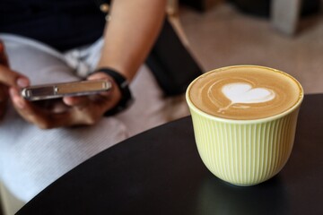 Woman using smart phone on hand and drink coffee cup