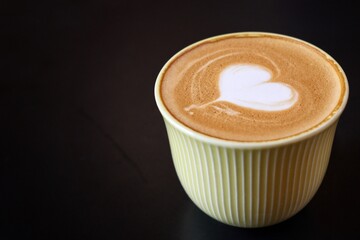 Heart of latte art coffee on black background