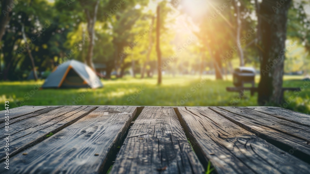 Wall mural A wooden table top topped with a blurry tent camping travel tent on grass. Clean and fresh concept for using for product display or design layouts. View of the copy space.