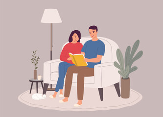 Smiling Couple Sitting On Couch Reading A Book Together.