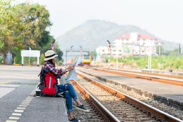 Naklejka premium Traveler and tourist asia young women wearing backpack holding map, waiting for a train. Travel Concept.