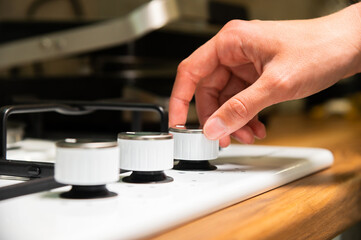 woman's hand rotates the selector on a gas stove. woman's hand turns on the burner on a gas stove