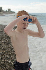 A boy puts on goggles to swim in the sea or ocean at a resort in the tropics, enjoying the summer sun.
