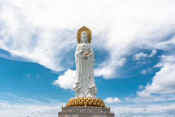SANYA, HAINAN, CHINA Buddhist deity statue Guainin with a tourist plane in the sky