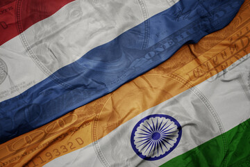 waving colorful flag of india and national flag of netherlands on the dollar money background. finance concept.