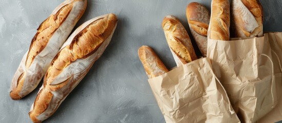 Fresh baguettes in paper bags on grey background with copy space image