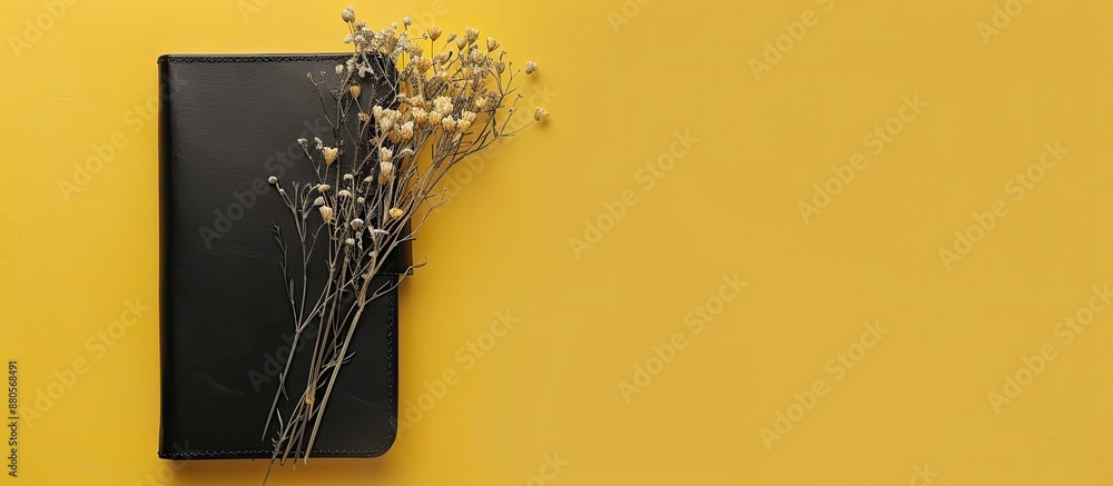Leinwandbilder business concept showcasing a black leather notebook adorned with dried flowers in a top view layout