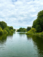 Beautiful lake surrounded by bushes and trees with a cloudy sky