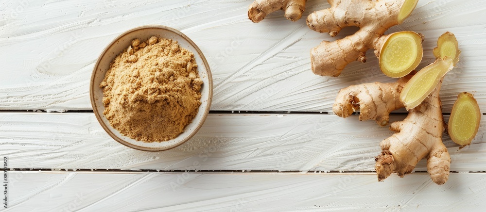 Aufkleber Top view of a small bowl with ground ginger and a ginger root on a white wooden backdrop with room for text or image. copy space available