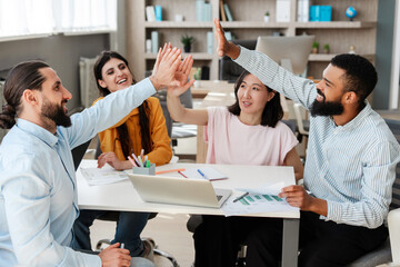 Happy diverse business team giving high five, celebrating success at office meeting