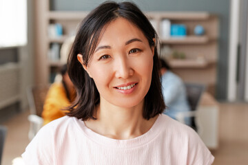 Beautiful asian woman smiling with teammates working in modern office, looking at camera