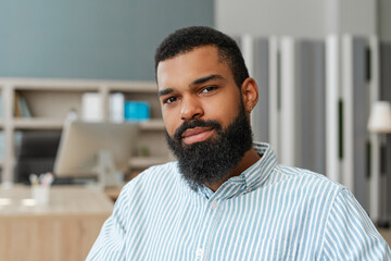 Obraz premium Confident young African American professional man posing in modern office looking at camera