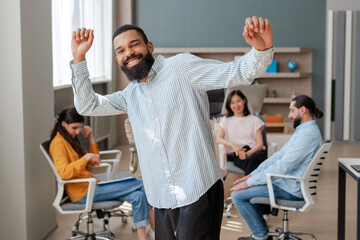 Young manager dancing with team celebrating success in modern office