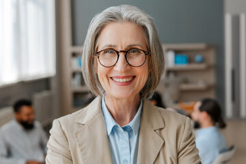 Senior businesswoman smiling in stylish eyeglasses, looking at camera posing in modern office
