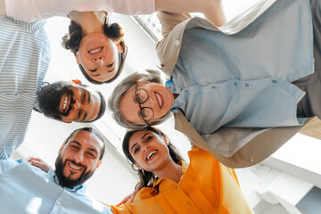 Group of diverse business people forming huddle and smiling at camera