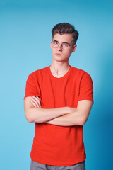 Colorful studio portrait of handsome young man in red t-shirt on blue background.