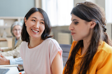 Obraz premium Asian woman smiling during business meeting with coworkers