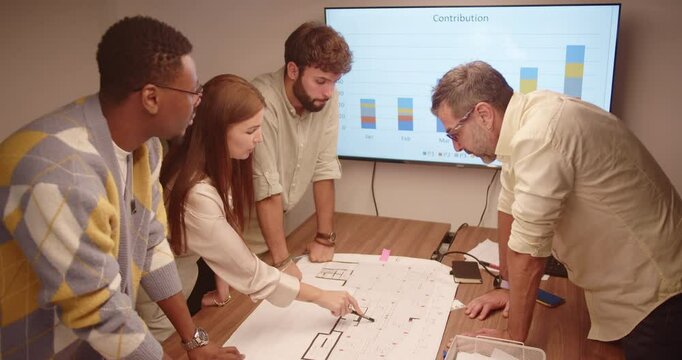 Multicultural business team discussing architectural blueprints in a conference room. Successful collaboration on an international start up project. Diverse executives and engineers working together.