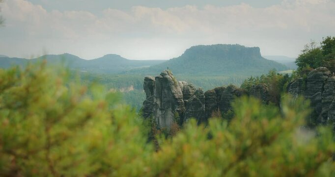 Rocky outcrop surrounded by trees with a hazy mountain backdrop and evergreen forest