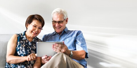 Senior couple using a digital device in a living room