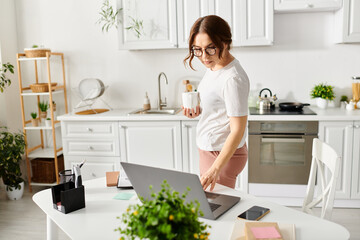 Middle-aged woman using laptop at kitchen table.