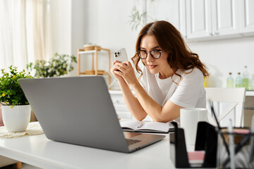 Middle-aged woman seated at table, engrossed in laptop work.