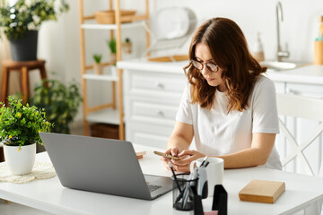 A middle-aged woman sitting at a table, engrossed in using a laptop computer.