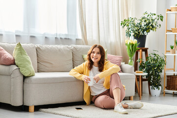 Middle-aged woman sits gracefully on floor in front of couch.