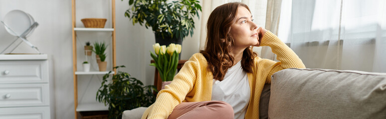 Middle-aged woman sitting on a couch, looking up thoughtfully.